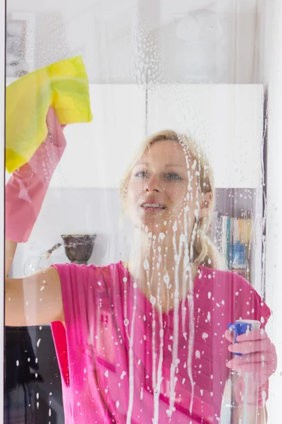 Femme au foyer avec gant de protection laver le verre de fenêtre — Photo