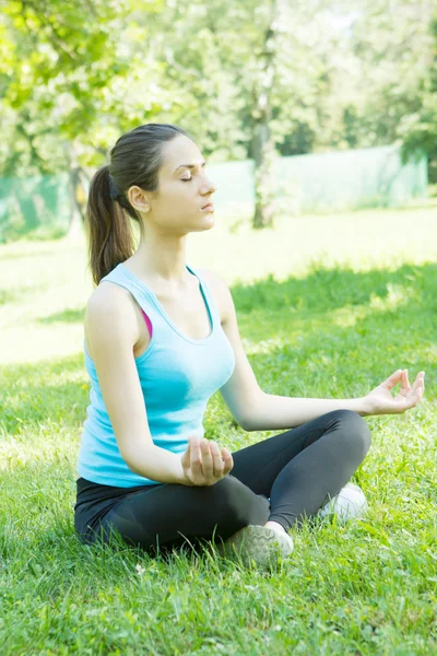 Genç bir kadın parkta meditasyon yapıyor. — Stok fotoğraf