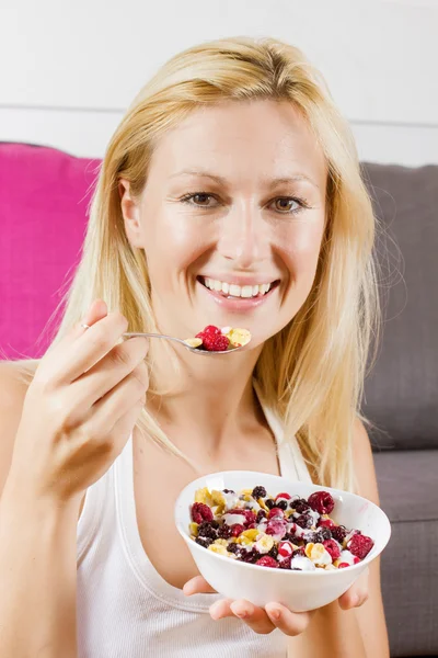 Retrato de una hermosa mujer rubia comiendo cereales con fruta en el desayuno —  Fotos de Stock