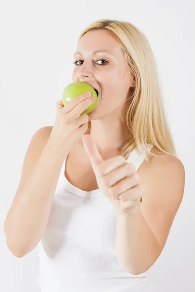 Schöne blonde Frau isst grünen Apfel lizenzfreie Stockfotos