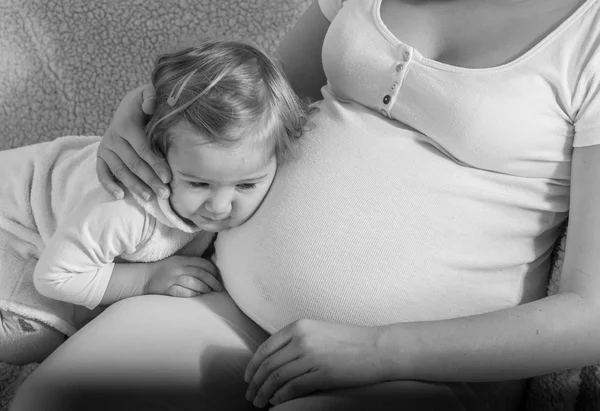Glückliches Kind lehnte ihren Kopf auf Bauch schwangere Frau. — Stockfoto