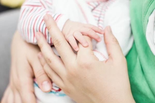 Мать держит новорожденного ребенка за руку — стоковое фото