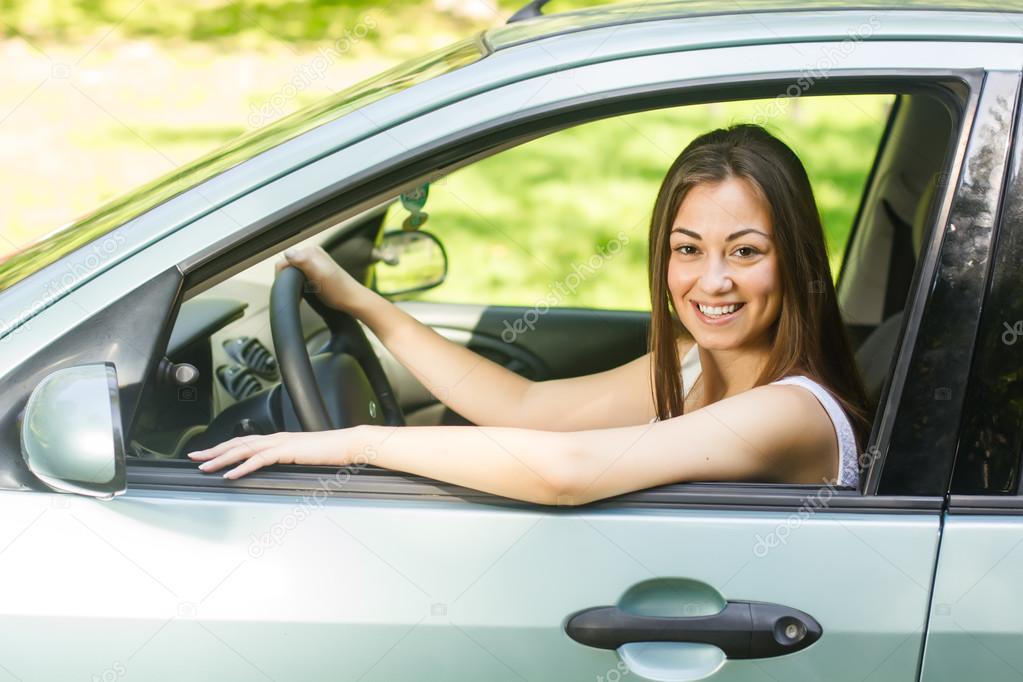 Happy young woman driving a car