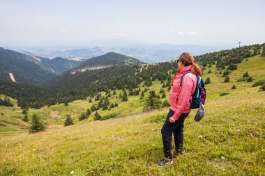 Kadın yürüyüşçü, yeşil vadi ve ormanın muhteşem manzarası. Sırbistan 'ın Kopaonik Dağı. Doğada yaz günü.