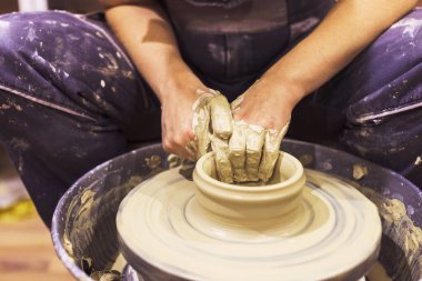 Çanak çömlek sanatçısı çömlek çarkında, sanat atölyesinde kilden vazo yapıyor..