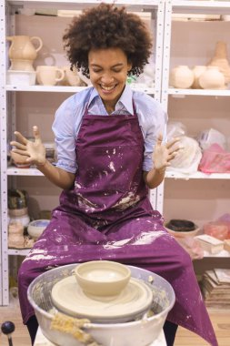 Sanat atölyesinde çömlek çarkında kille çalışan kadın çömlek sanatçısı..