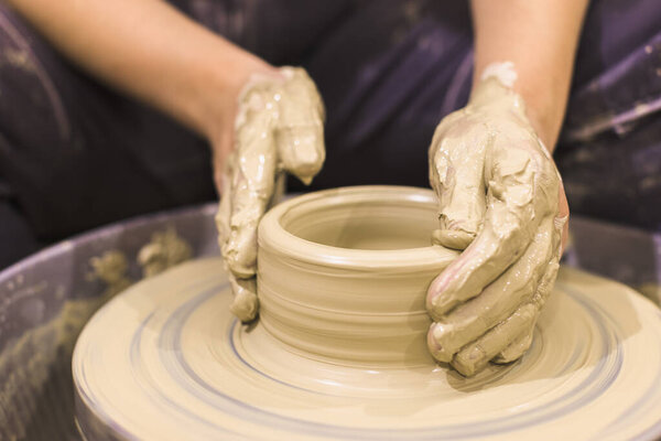 Pottery artist hands molding clay vase on pottery wheel , art workshop.
