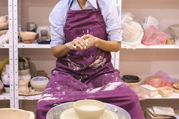 Kadın seramik sanatçısı sanat atölyesinde çömlek çarkında kil kalıbı çıkarıyor..