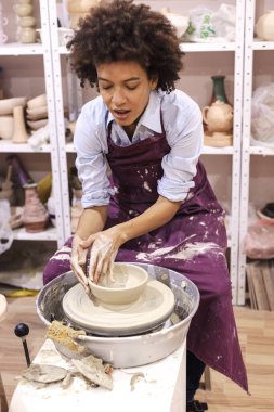 Çömlek çarkında kil şekillendiren yaratıcı Afro-Amerikan genç kadın. Seramik stüdyosunda atölye.