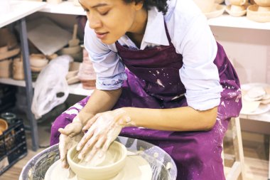 Çömlek çarkında kil şekillendiren yaratıcı Afro-Amerikan genç kadın. Seramik stüdyosunda atölye.