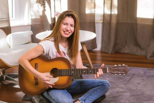 Evde akustik gitar çalan güzel bir kadının portresi. Müzik aleti çalmayı öğreniyorum. Boş zaman hobisi. Boş zaman .