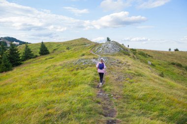 Sırt çantalı küçük bir kız dağ yolunda yürüyüş, güzel bir yaz günü, dağ manzarası. Çocuk aktivitesi..
