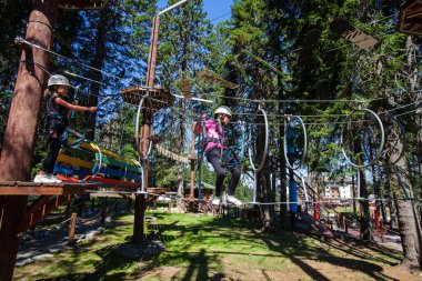 Çocuklar macera parkına tırmanırken güvenlik ekipmanı kullanıyorlar. Çocuk açık hava sporları aktivitesi.  