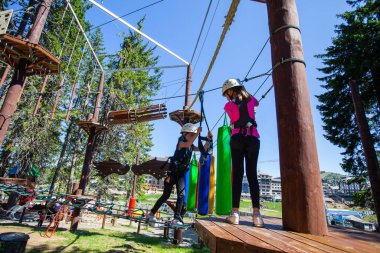Çocuklar macera parkına tırmanırken güvenlik ekipmanı kullanıyorlar. Çocuk açık hava sporları aktivitesi.  