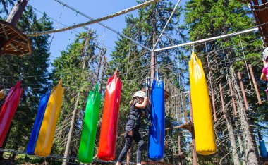 Çocuk macera eğlence parkında güvenlik ekipmanı kullanıyor. Genç kız dışarıda eğleniyor. Çocukluk aktif. Aşırı spor faaliyetleri.