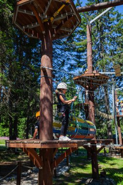 Çocuk macera eğlence parkında güvenlik ekipmanı kullanıyor. Genç kız dışarıda eğleniyor. Çocukluk aktif. Aşırı spor faaliyetleri.