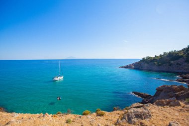 Bir yaz günü, kristal turkuaz renk denizinin körfezinde yelkenli teknesiyle güzel bir deniz manzarası. Yaz tatili yatı. Thassos Adası, Yunanistan.
