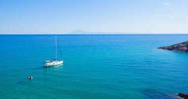 Bir yaz günü, kristal turkuaz renk denizinin körfezinde yelkenli teknesiyle güzel bir deniz manzarası. Yaz tatili yatı. Thassos Adası, Yunanistan.