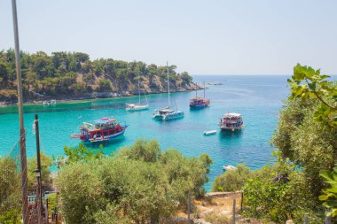 Denizin muhteşem kristal turkuaz renginde turistik tekneleri var. Doğal çevrenin huzuru. Yaz yolculuğu konsepti.