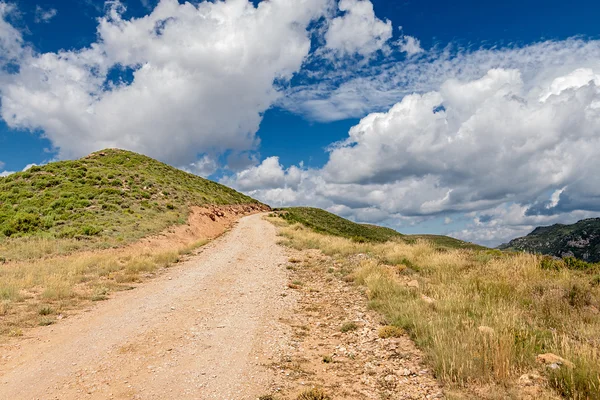 Caminho nas montanhas sob o céu dramático — Fotografia de Stock