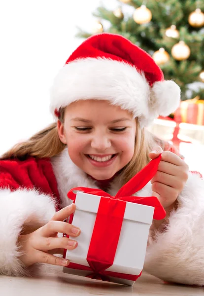 Gelukkig jong meisje lachend met de doos van de gift in de buurt van de kerstboom. — Stockfoto