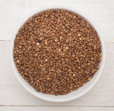 Ahşap arka planda bir kasede pişmemiş karabuğday manzarası