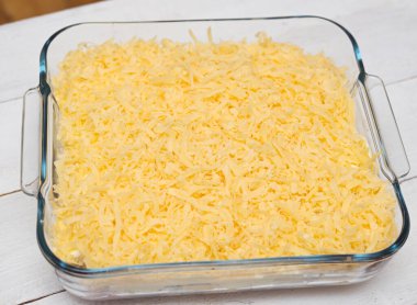 Ahşap bir arka planda şeffaf tepside pişmemiş lazanya manzarası