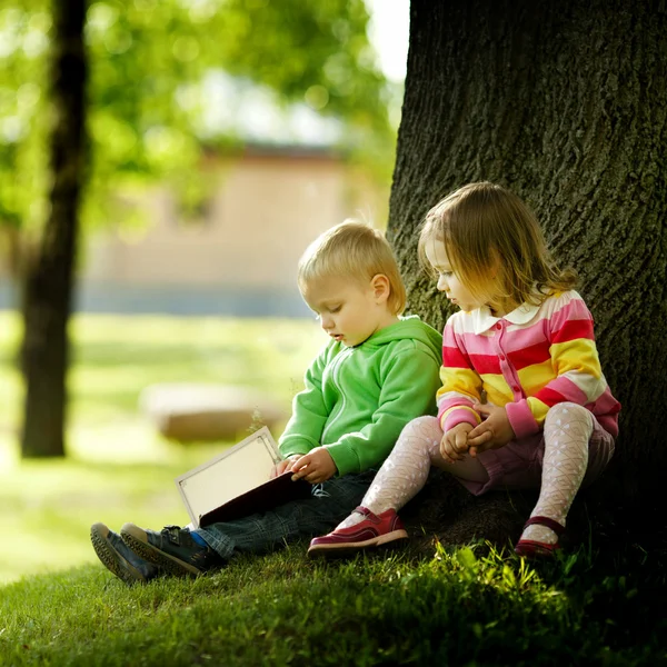 Menino bonito e menina lendo um livro — Fotografia de Stock