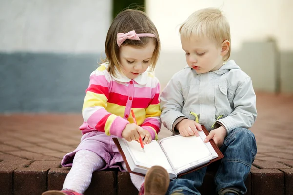 Мальчик и девочка пишут в блокнот — стоковое фото