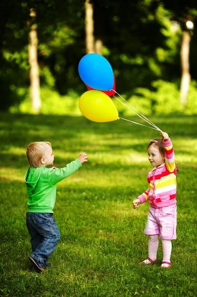 Flicka och en pojke leker med ballonger i park — Stockfoto