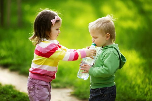 Niño y niña compartiendo botella de agua — Foto de Stock