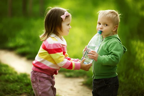 Niño y niña compartiendo botella de agua —  Fotos de Stock