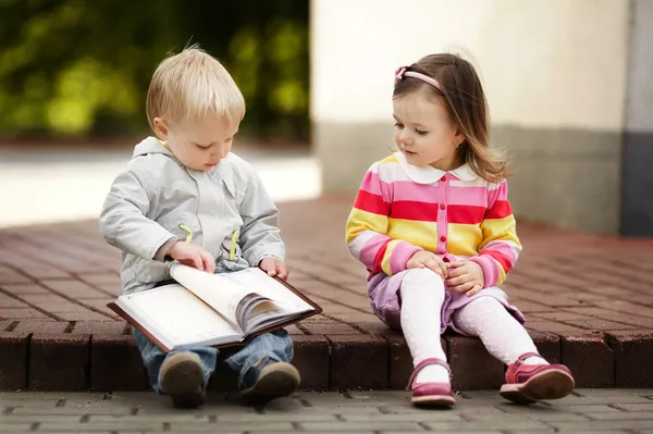 Jongen en meisje lezen boek Stockfoto