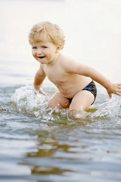 Liten rolig pojke spelar i vatten — Stockfoto