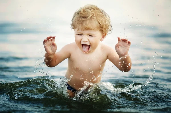 Menino engraçado brincando na água — Fotografia de Stock