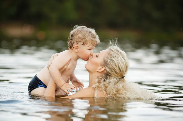 Beautiful young mother with son in water — Stockfoto