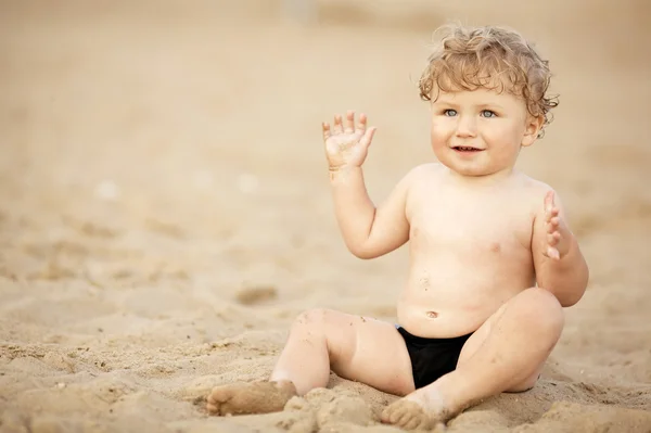 Pequeno engraçado menino joga na praia — Fotografia de Stock