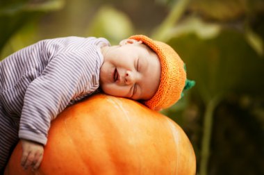 Baby sleeping on big pumpkin