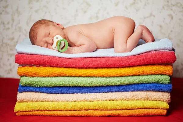 Niedliches Neugeborenes liegt auf bunten Handtüchern — Stockfoto