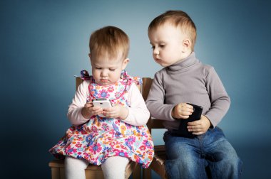 Little boy and girl playing with mobile phones clipart