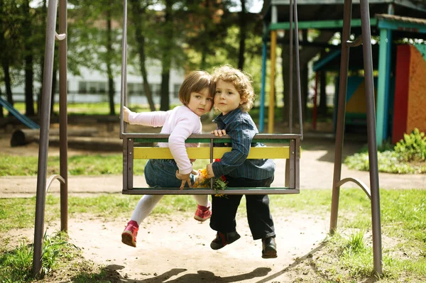Boy and girl on the swings — Stock Photo, Image