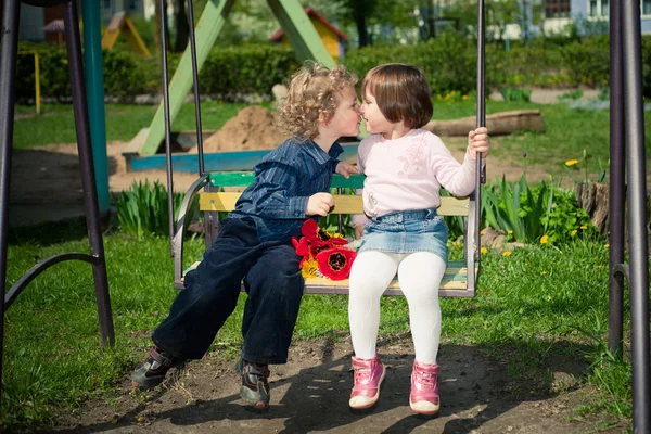 Niño y niña en los columpios — Foto de Stock