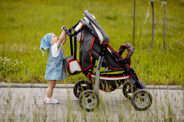 Маленька смішна дівчинка з дитячою коляскою — стокове фото