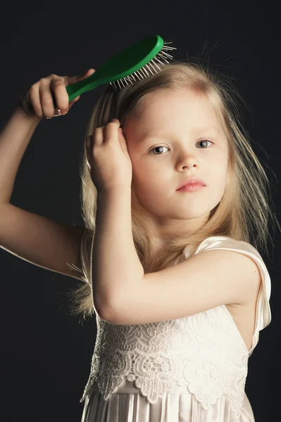 Holčička česání dlouhé krásné vlasy — Stock fotografie