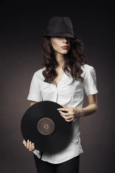 Beautiful brunette girl with vinyls on dark background — Stock Photo, Image