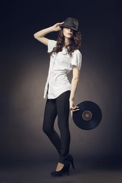 Krásná brunetka s vinyly na tmavém pozadí — Stock fotografie