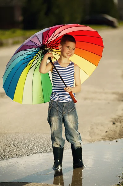 Liten flicka med en regnbåge paraply i park — Stockfoto