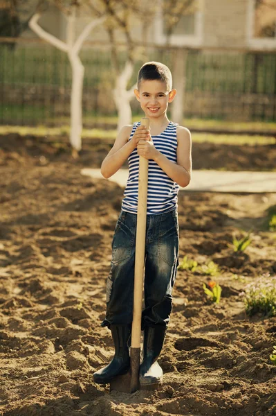 Malý chlapec s lopatou v zahradě — Stock fotografie