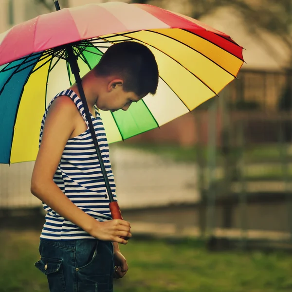 Smutny chłopiec withl tęcza parasol — Zdjęcie stockowe