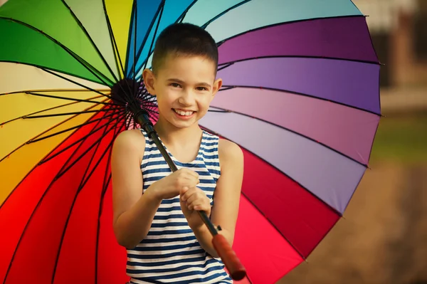 Little girl with a rainbow umbrella in park — Stock Photo, Image